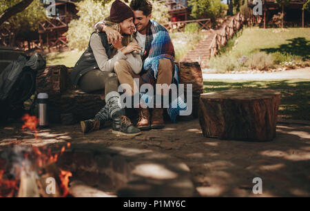 Romantisches Paar auf dem Campingplatz sitzen. Der Mann und die Frau sitzt auf einem Anmelden bei Camping mit Lagerfeuer vor. Stockfoto