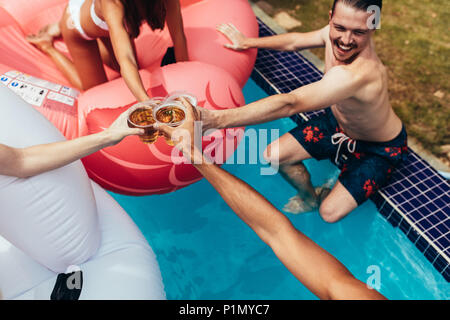 Gruppe von Freunden feiern in einem Pool und in Biere. Freunde toasten Bier am Pool Party. Stockfoto