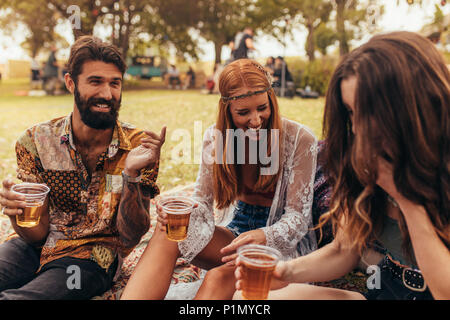 Gerne Freunde feiern im Park mit Getränken. Eine Gruppe von Freunden eine Party zusammen im Park. Stockfoto