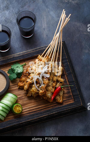 In der Nähe der malaysischen Hähnchenspieße - Satay oder Sate Ayam mit Erdnuss-sauce, dunklen Hintergrund. Stockfoto