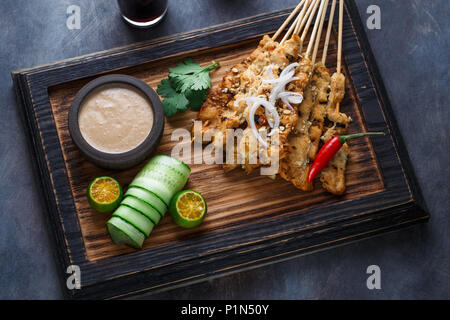 In der Nähe der malaysischen Hähnchenspieße - Satay oder Sate Ayam mit Erdnuss-sauce, dunklen Hintergrund. Stockfoto