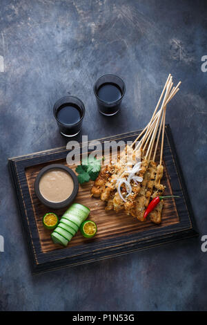 Chicken Satay oder Sate Ayam - Malaysisch berühmten Essen. Ist ein Gericht der gewürzt, aufgespießt und gegrilltes Fleisch, serviert mit Erdnusssoße. Darkphoto. Ansicht von oben Stockfoto