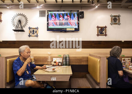 Kowloon, Hong Kong. 12 Juni, 2018. In einem lokalen Restaurant in Hongkong, einem lokalen Uhren ein TV-Bildschirm angezeigt, der die historischen Moment, wenn US-Präsident Donald Trump und Nordkorea Kim Jong-un zum ersten Mal während der Singapur Frieden erfüllen und die entnuklearisierung Gipfel. Credit: Miguel Candela/SOPA Images/ZUMA Draht/Alamy leben Nachrichten Stockfoto