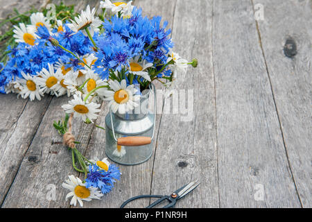 Blumensträuße der schönen wilden Blüten der Gänseblümchen und Kornblumen auf einer hölzernen alten Hintergrund. Herzliche Gratulation. Stockfoto