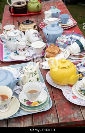 Fertige Tassen Tee und Kaffee Töpfen auf einen Tisch draußen Kaffee eine Blume zeigen. Großbritannien Stockfoto