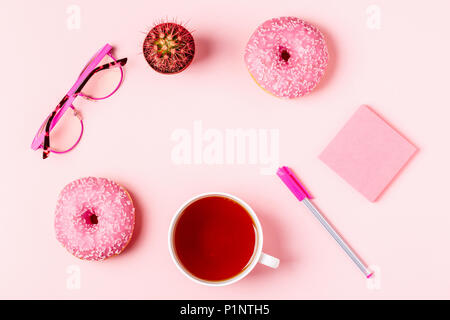 Tasse Tee mit Donuts auf einem Rosa pastell Hintergrund, Ansicht von oben. Stockfoto