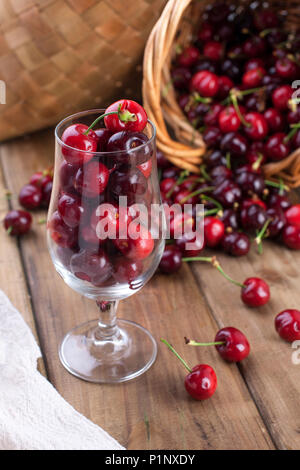 Viel reifer und Süßkirschen, auf dem Tisch und im Glas, für traditionelles belgisches Bier. Köstlich rote Beeren. Platz kopieren Stockfoto