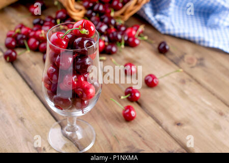 Viel reifer und Süßkirschen, auf dem Tisch und im Glas, für traditionelles belgisches Bier. Köstlich rote Beeren. Platz kopieren Stockfoto