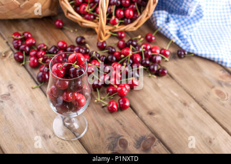 Viel reifer und Süßkirschen, auf dem Tisch und im Glas, für traditionelles belgisches Bier. Köstlich rote Beeren. Platz kopieren Stockfoto