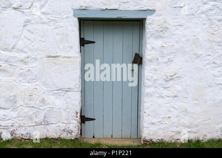 Alte Blaue verwitterten hölzernen Tür auf einem weiß getünchten Gebäude aus Stein Stockfoto