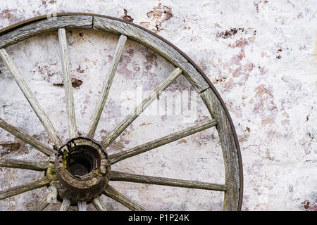 Alten hölzernen Wagen Rad lehnte sich gegen die Mauer aus Stein Stockfoto