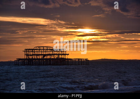 Die Sonne hinter der berühmten Brighton West Pier Ruinen Stockfoto