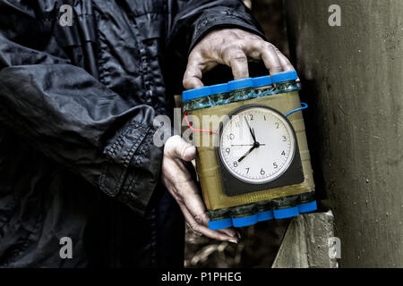 Terroristische Holding eine zeitgesteuerte Bombe in seinen Händen. Gefährliche Angreifer und Dummy der Sprengsatz. Idee der Terroranschlag, Sicherheit und Schutz. Stockfoto