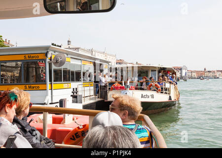 Reisen mit überfüllten Vaporetto Wasserbus in Venedig, Venetien, Italien mit Massen von Menschen Einsteigen in ein Boot an der Haltestelle San Marco in der ersten Person P Stockfoto