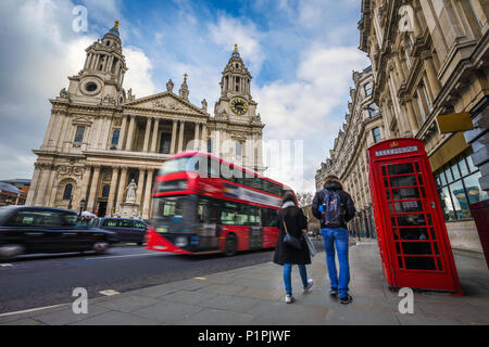 London, England - Touristische Paar zu Fuß durch ein traditionelles rotes Feld mit roten Doppeldecker Bus und Taxi unterwegs im Hintergrund an der St. Stockfoto