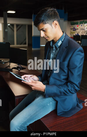 Junge tausendjährigen Geschäftsmann mit seiner Technologie am Arbeitsplatz; Sherwood Park, Alberta, Kanada Stockfoto