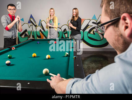 Eine Gruppe junger tausendjährigen Geschäftsleute ein Spiel der Pool auf einer Arbeit brechen; Sherwood Park, Alberta, Kanada Stockfoto