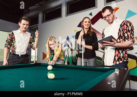 Eine Gruppe junger tausendjährigen Geschäftsleute ein Spiel der Pool auf einer Arbeit brechen; Sherwood Park, Alberta, Kanada Stockfoto