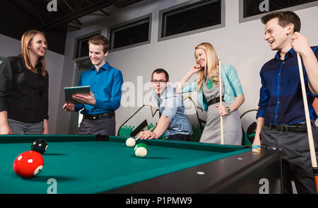 Eine Gruppe junger tausendjährigen Geschäftsleute ein Spiel der Pool auf einer Arbeit brechen; Sherwood Park, Alberta, Kanada Stockfoto