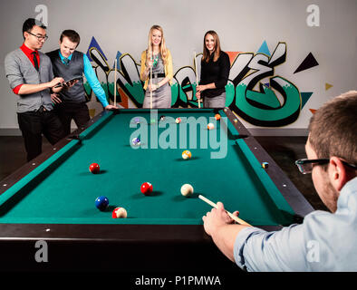 Eine Gruppe junger tausendjährigen Geschäftsleute ein Spiel der Pool auf einer Arbeit brechen; Sherwood Park, Alberta, Kanada Stockfoto