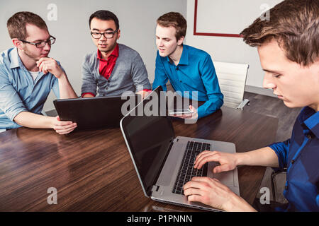 Junge Männer, die tausendjährige Geschäftsleute zusammen in einem Konferenzraum in einem High-Tech modernes Unternehmen arbeiten Stockfoto
