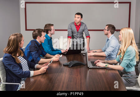 Junge tausendjährigen Geschäftsmann sprach mit einer Gruppe junger Fachleute in einem Konferenzraum in einem Geschäft; Sherwood Park, Alberta, Kanada Stockfoto