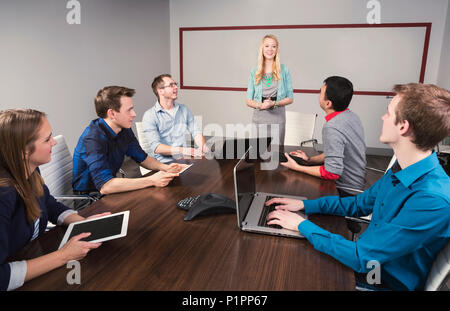 Junge tausendjährigen Geschäftsfrau im Gespräch mit einer Gruppe junger Fachleute in einem Konferenzraum in einem Geschäft; Sherwood Park, Alberta, Kanada Stockfoto