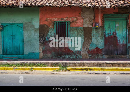 Getragen und verwitterte Fassade eines Gebäudes mit abblätternder Farbe und doppelten Türen; Nicaragua Stockfoto