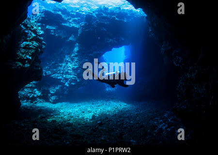 Scuba Diver schwimmt durch Lava Bögen mit Sonnenstrahlen, Kathedralen Tauchplatz; Lanai City, Lanai, Hawaii, Vereinigte Staaten von Amerika Stockfoto