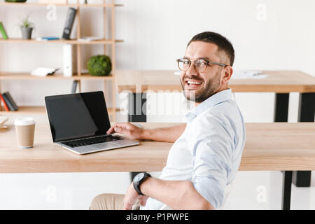 Halbe Umdrehung Foto von Ihnen Büro Mann 30 s im weißen Hemd sitzt am Tisch, und wenn man die Kamera während der Arbeit am Laptop im Business Center Stockfoto