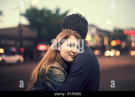 Ein junges Paar steht, die auf einem Gehweg in einer beliebten Gegend in der Dämmerung; Edmonton, Alberta, Kanada Stockfoto