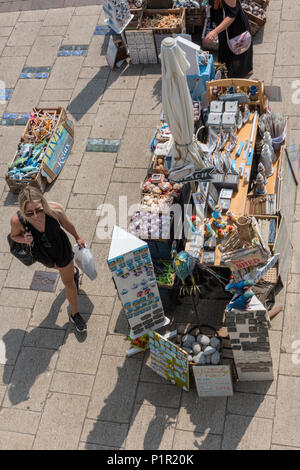 Eine attraktive junge Frau mit schwarzen und Sonnenbrillen zu Fuß durch ein Geschenk ein Souvenir am Strand von Brighton, East Sussex, UK. Strand Geschenk Shop. Stockfoto