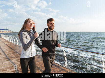 Sportlich junges Paar joggen zusammen am Strand Stockfoto
