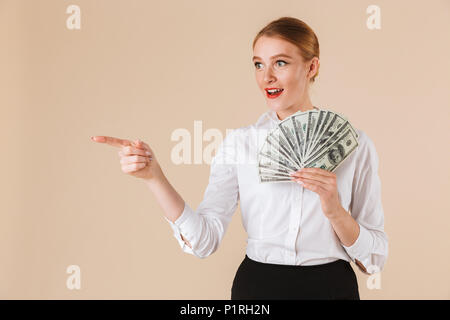 Porträt eines lächelnden Geschäftsfrau mit Geld Banknoten und Zeigefinger bei copy Raum über beigen Hintergrund isoliert Stockfoto