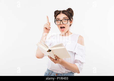 Junge intelligente Studentin oder Schülerin mit einem Brötchen Frisur und Zahnspangen Zeigefinger nach oben beim Lesen Buch über Weiß b isoliert Stockfoto