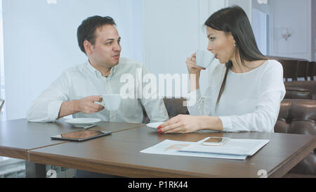 Zwei freundliche Mitarbeiter sprechen über Kaffee in einem Cafe Stockfoto