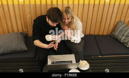 Glückliches Paar in on-line-Konferenz auf Laptop in einem Restaurant Stockfoto