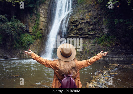 Frau in Hat sich Ihre Hand in der Nähe des Wasserfalls im Botanischen Garten in Tiflis, Georgien Stockfoto