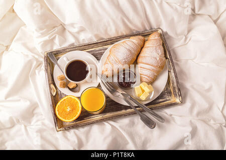 Köstliches Frühstück im Bett mit Kaffee und Croissants. Stockfoto