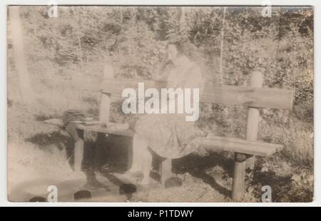 Die tschechoslowakische Republik - circa 1930s: Vintage Foto zeigt eine junge Frau auf der Bank im Wald sitzt. Retro Schwarz/Weiß-Fotografie. Mit original Film Grain, Blur und Kratzern. Stockfoto