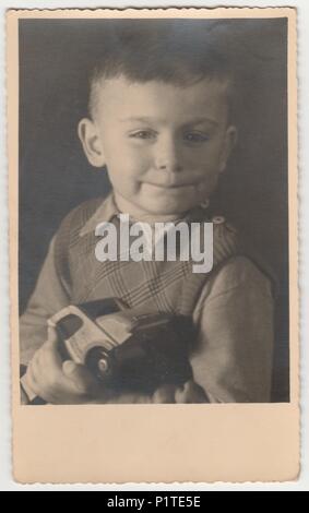 MAGDEBURG, Deutschland - circa 1940s: Vintage Foto zeigt Junge hält Spielzeugautos. Schwarz/Weiß-Fotografie Stockfoto