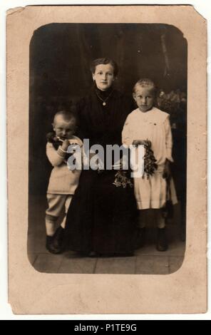 Deutschland - circa 1930s: photo Vintage zeigt die Frau und ihre Kinder in ein Fotostudio. Junge trägt eine Sailor Girl Kostüm und weißes Kleid. Retro black & white Studio Fotografie mit Sepia Effekt. Stockfoto