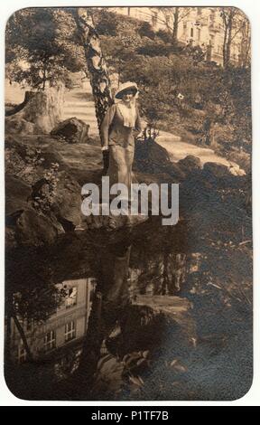 Die tschechoslowakische Republik - circa 1930s: Vintage Foto zeigt Frau trägt ein elegantes Kleid und Federhut. Die Frau wirft im Freien am Ufer des Flusses. Retro Schwarz/Weiß-Fotografie. Stockfoto