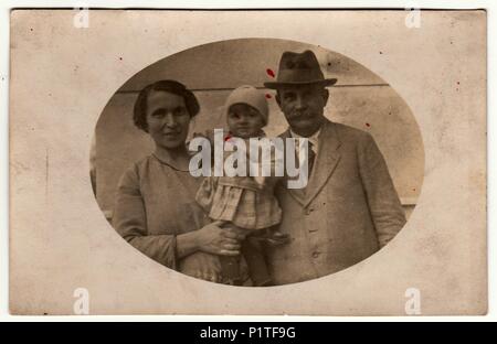 KOVCIN U OLSAN, der Tschechoslowakischen Republik - Dezember 20, 1923: Vintage Foto zeigt Mutter hält ein kleines Baby und Vater. Retro Schwarz/Weiß-Fotografie. Stockfoto