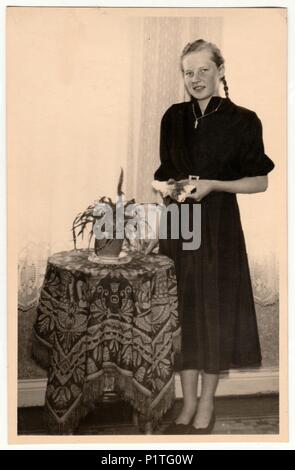 Die tschechoslowakische SOZIALISTISCHE REPUBLIK - circa 1950s: Vintage Foto zeigt ein junges Mädchen am Tisch im Wohnzimmer dar. Retro Schwarz/Weiß-Fotografie. Stockfoto