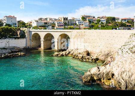 Blick auf die Bucht und die Brücke von fausse Monnaie (wörtlich "Falschgeld") in Endoume Bezirk mit Menschen beim Sonnenbaden auf den Felsen und Schwimmen in t Stockfoto