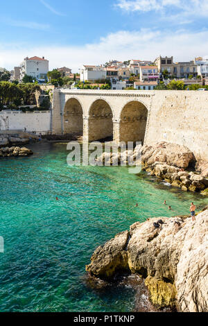 Blick auf die Bucht und die Brücke von fausse Monnaie (wörtlich "Falschgeld") in Endoume Bezirk mit Menschen beim Sonnenbaden auf den Felsen und Schwimmen in t Stockfoto