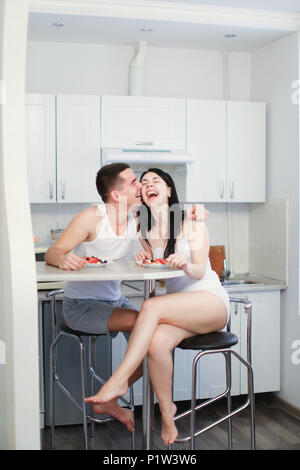 Lächelnd, Mann und Frau, das Frühstück in der Küche, zwei Platten mit Porridge und Beeren. Stockfoto