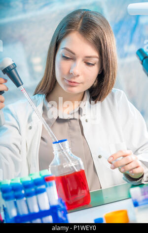 Junge Frau im wissenschaftlichen Labor mit Pipette und Chemikalien in den Reagenzgläsern Stockfoto