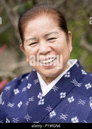 Lächelnd alten Okinawanischen Frau in traditionellen leichte Sommer kimono an der Ryukyu Mura, Joensuu, Okinawa. Stockfoto